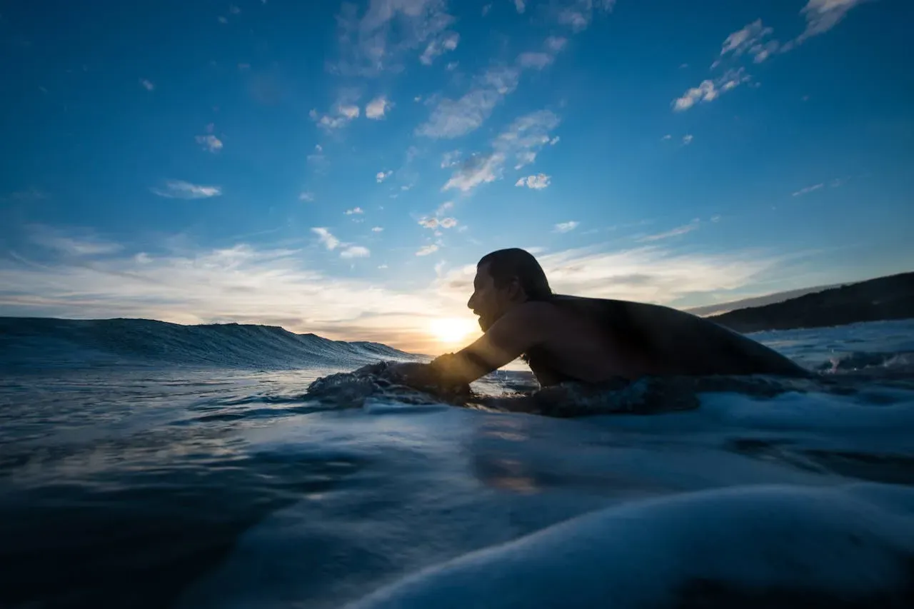 Secret Surf Spot man swimming in the water on his board early in the morning sunrise | Picture by Emiliano Arano: https://www.pexels.com/de-de/foto/mann-der-wahrend-der-blauen-stunde-surft-1330217/